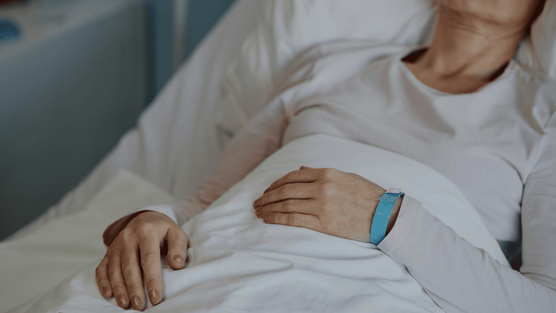 Patiënt rust comfortabel in een ziekenhuisbed met medische polsband in een zorgomgeving