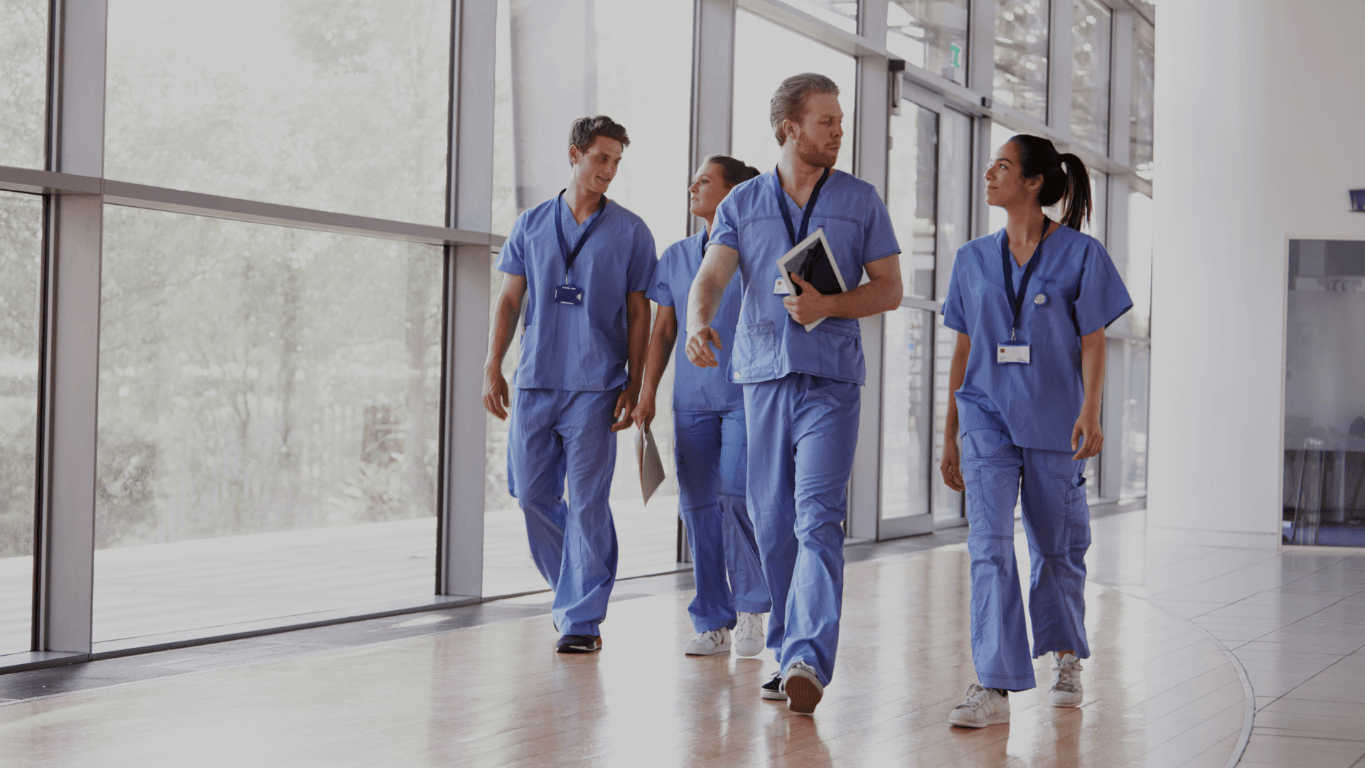 vier zorgmedewerkers aan het wandelen in de gang van het ziekenhuis