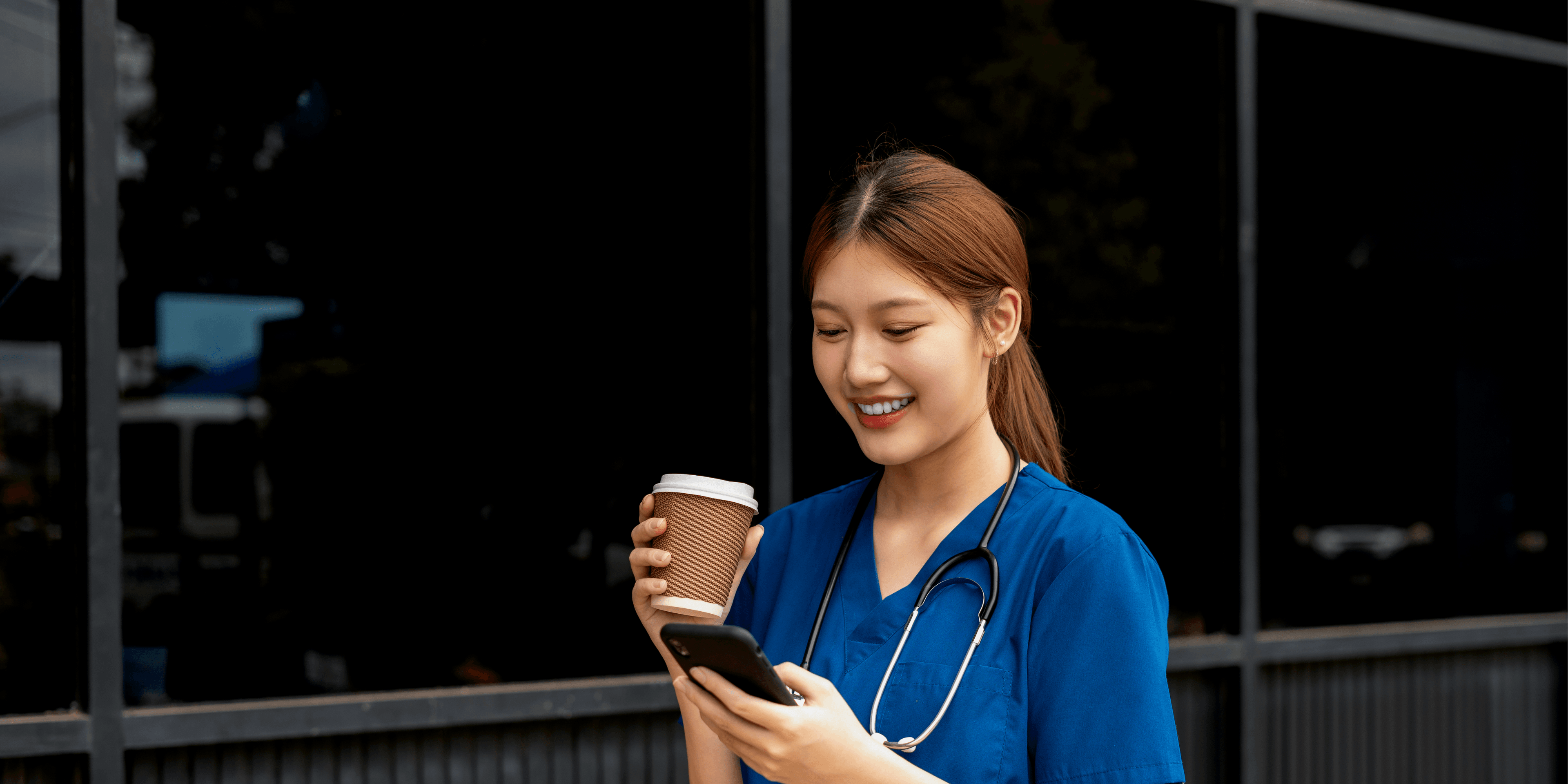Ziekenhuismedewerker met pauze drinkt koffie en zit op haar telefoon tjdens wandeling