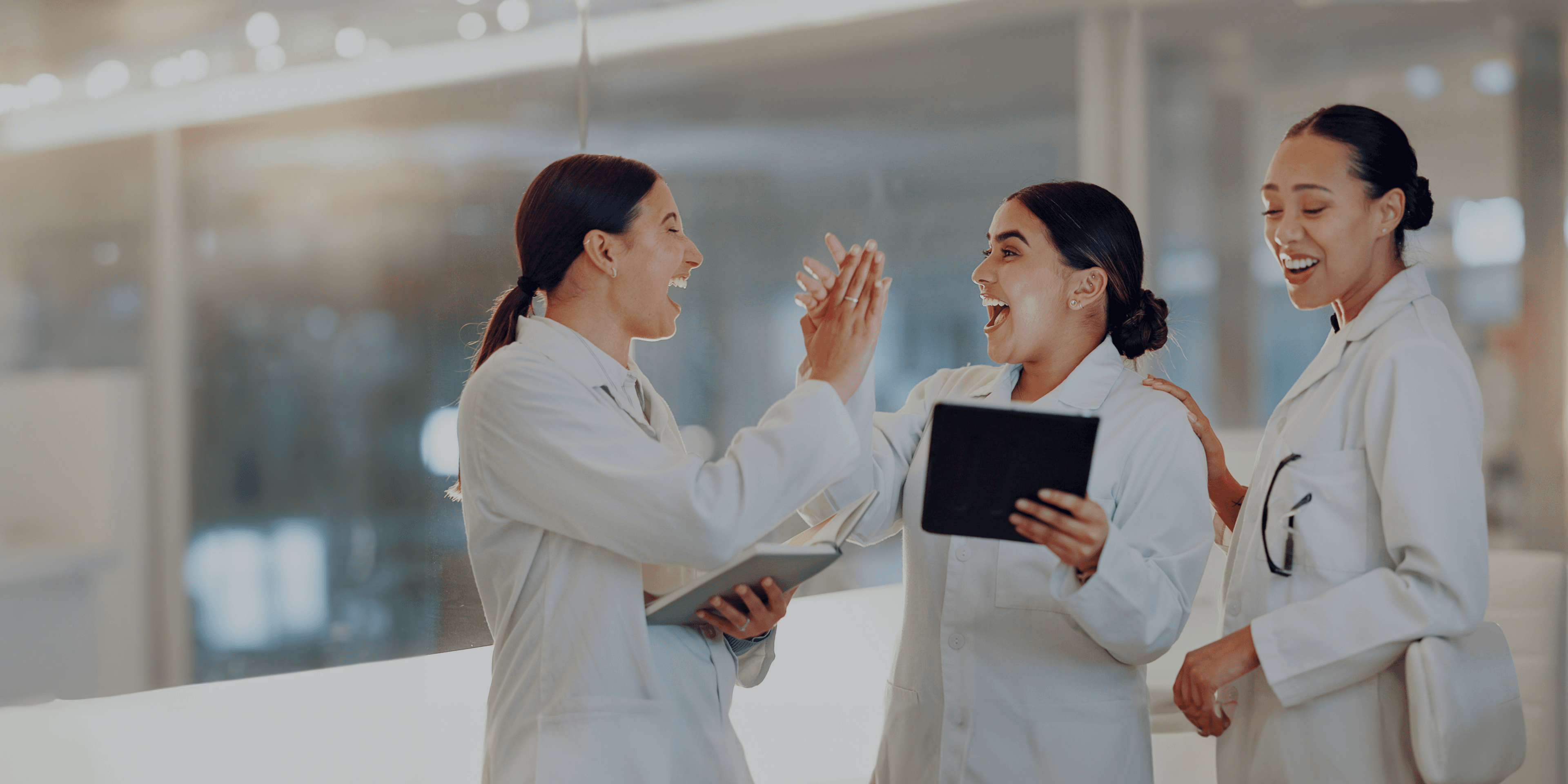 3 blije artsen in een ziekenhuis die elkaar een high-five geven