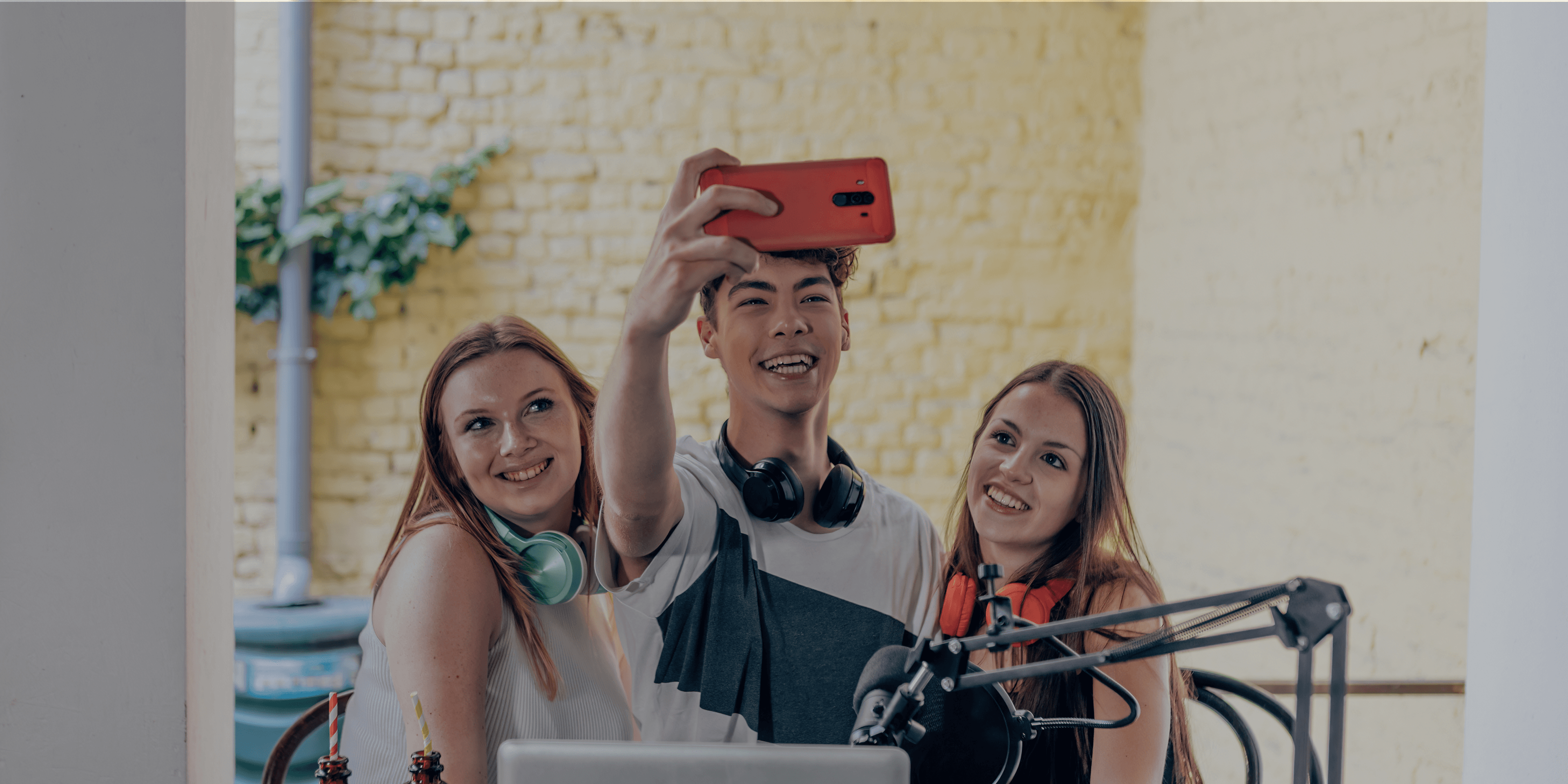 3 jongeren die een podcast opnemen en ondertussen een selfie maken in een studio