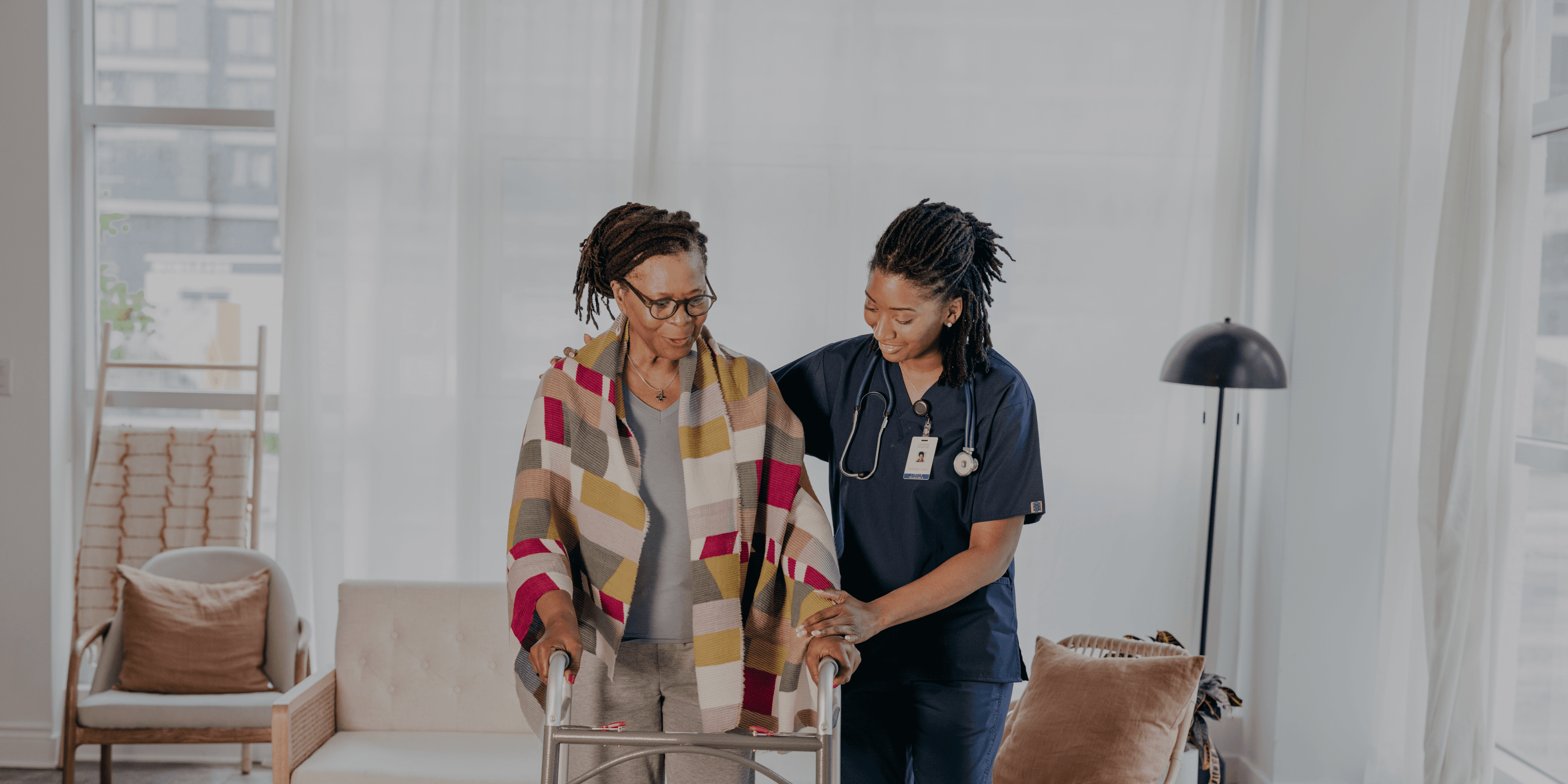 Zorgmedewerker helpt vrouw met rollator lopen in woonzorgcentrum